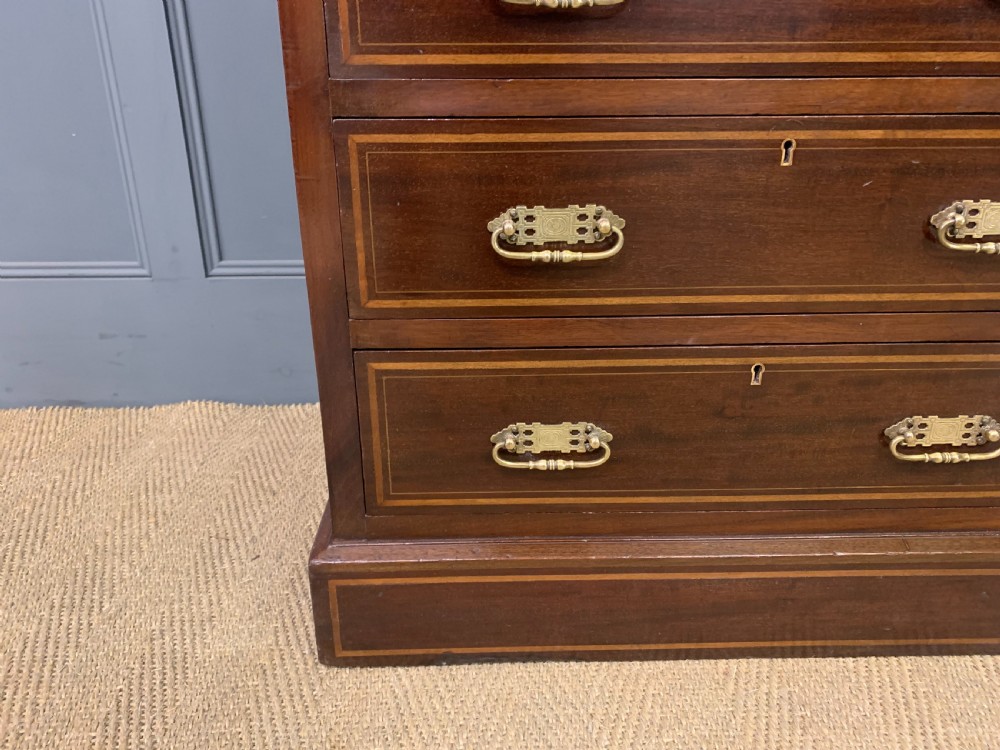 A tall Edwardian mahogany pillar chest featuring seven inlaid drawers with brass drop handles on a plinth base. View VII