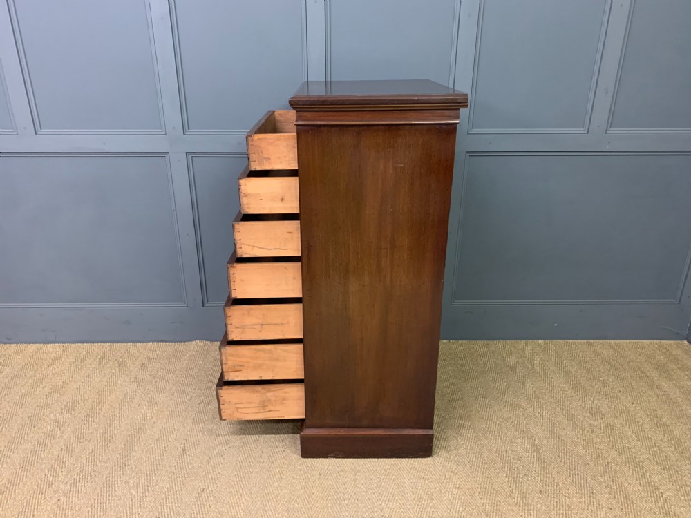 A tall Edwardian mahogany pillar chest featuring seven inlaid drawers with brass drop handles on a plinth base. View XIV