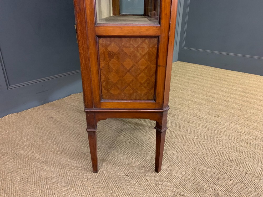 An Edwardian walnut and kingwood display cabinet featuring three glazed doors, parquetry panel lower sections, and a central arched pediment with a gilt mount. View X