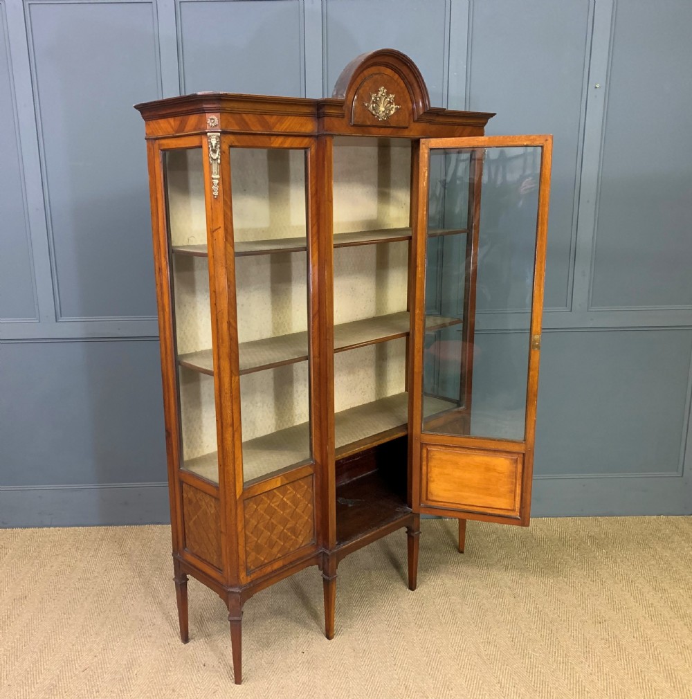 An Edwardian walnut and kingwood display cabinet featuring three glazed doors, parquetry panel lower sections, and a central arched pediment with a gilt mount. View XIII