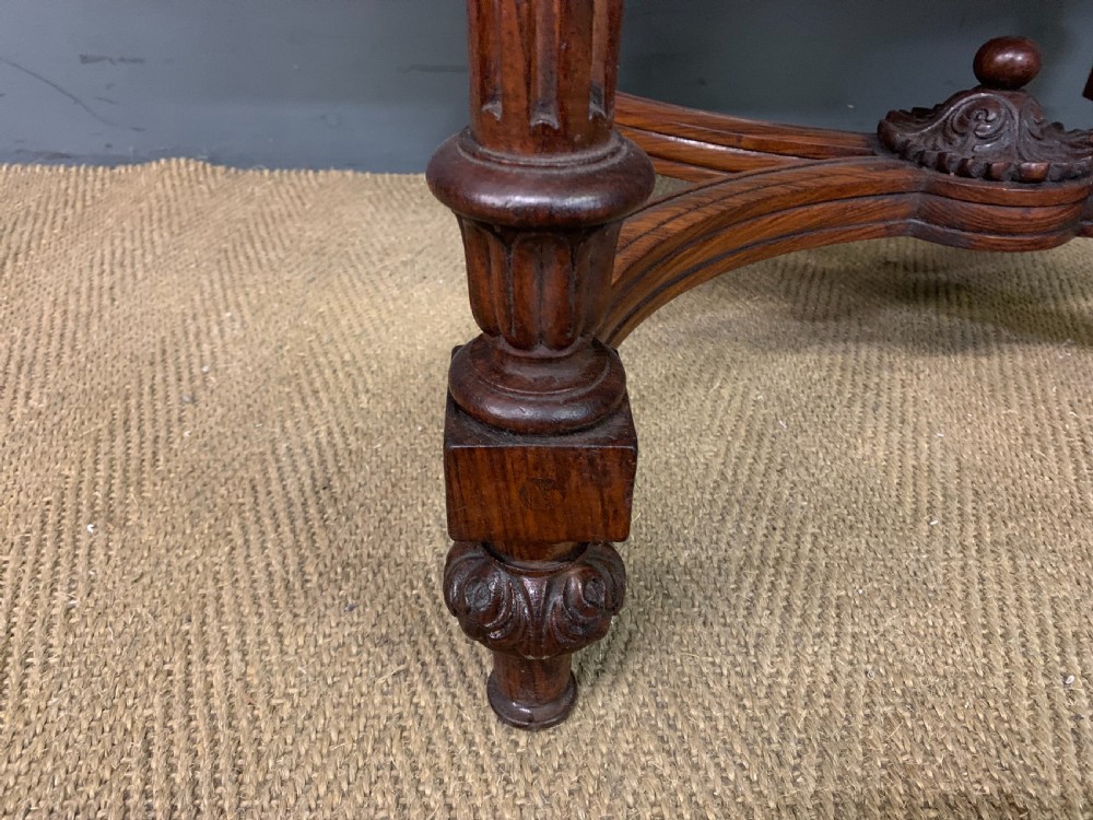 An Anglo-Indian rosewood games table featuring an inlaid square chessboard top, drop leaves, a carved frieze, and turned legs connected by a curved stretcher. View VII