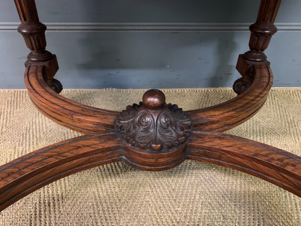 An Anglo-Indian rosewood games table featuring an inlaid square chessboard top, drop leaves, a carved frieze, and turned legs connected by a curved stretcher. View VIII