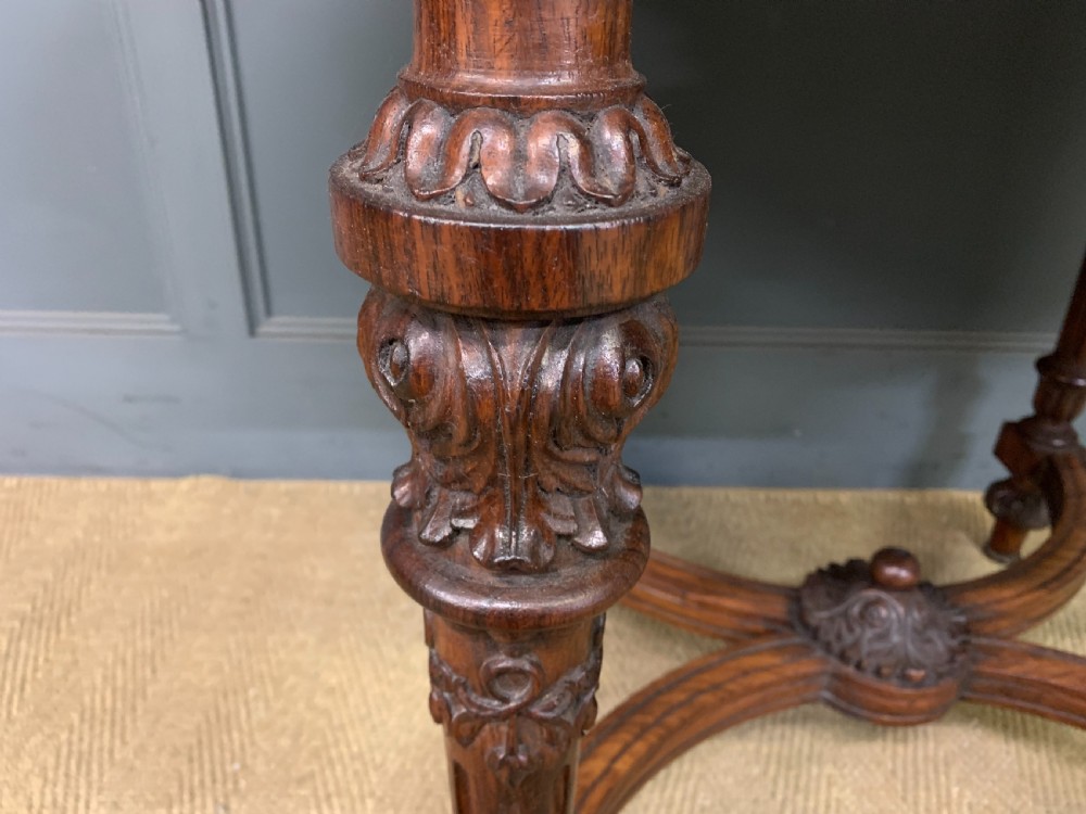 An Anglo-Indian rosewood games table featuring an inlaid square chessboard top, drop leaves, a carved frieze, and turned legs connected by a curved stretcher. View IX