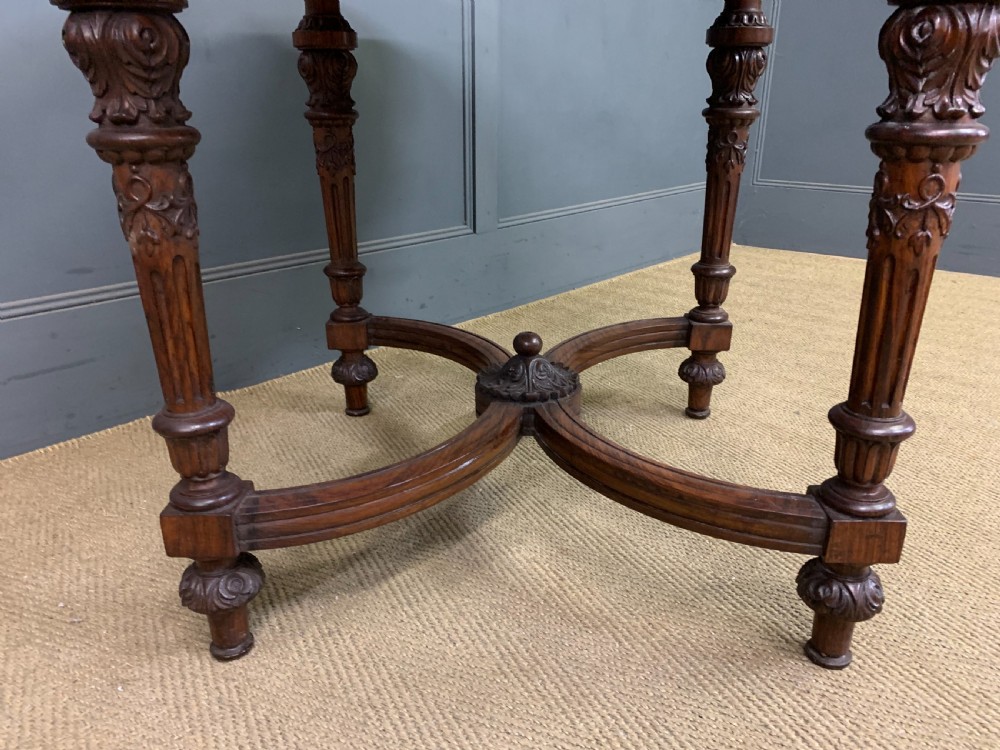 An Anglo-Indian rosewood games table featuring an inlaid square chessboard top, drop leaves, a carved frieze, and turned legs connected by a curved stretcher. View XIV