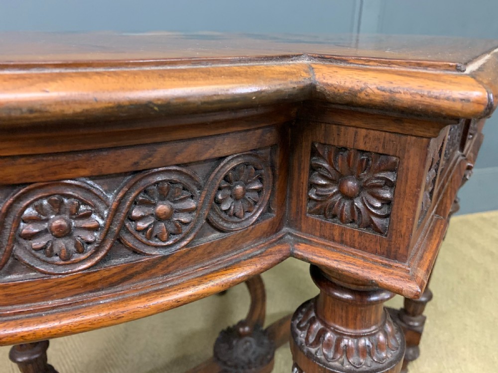 An Anglo-Indian rosewood games table featuring an inlaid square chessboard top, drop leaves, a carved frieze, and turned legs connected by a curved stretcher. View XV