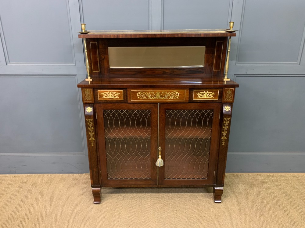 An antique Regency rosewood chiffonier featuring ornate brass inlay, a top mirror back with a brass gallery rail, and twin doors with brass wire mesh. View II