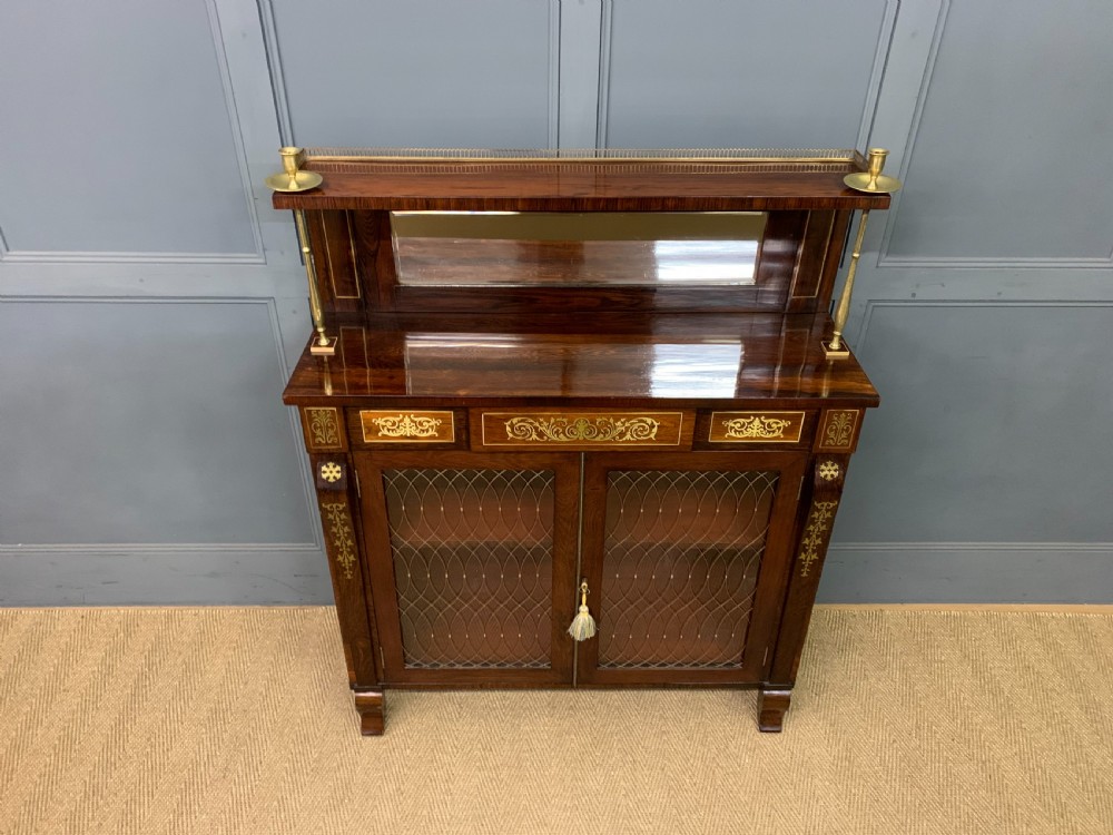 An antique Regency rosewood chiffonier featuring ornate brass inlay, a top mirror back with a brass gallery rail, and twin doors with brass wire mesh. View III