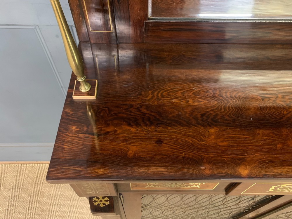 An antique Regency rosewood chiffonier featuring ornate brass inlay, a top mirror back with a brass gallery rail, and twin doors with brass wire mesh. View V