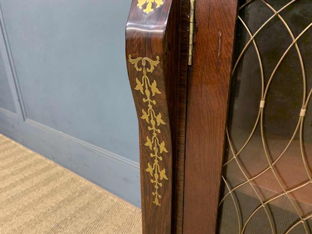 An antique Regency rosewood chiffonier featuring ornate brass inlay, a top mirror back with a brass gallery rail, and twin doors with brass wire mesh. View XIII