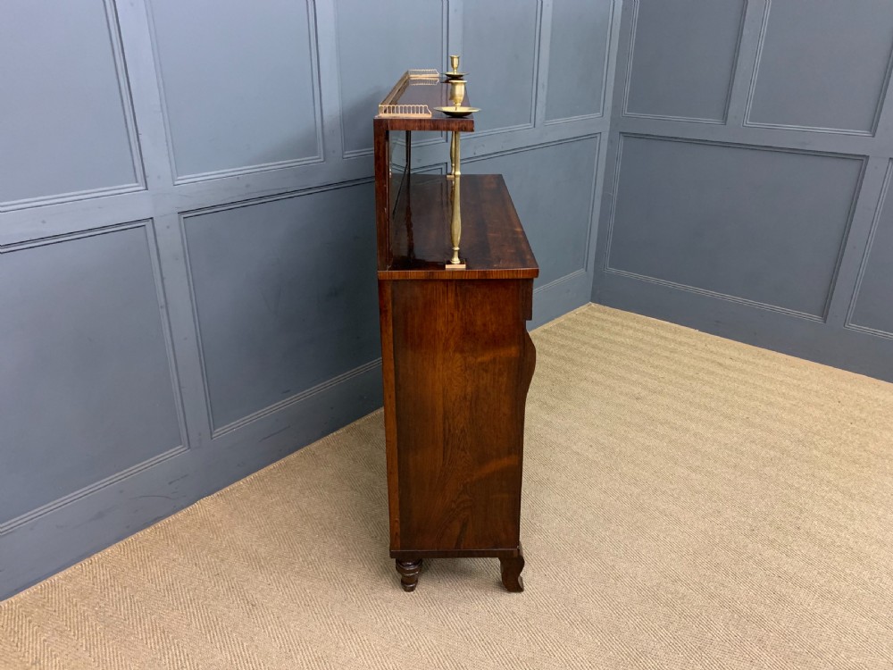 An antique Regency rosewood chiffonier featuring ornate brass inlay, a top mirror back with a brass gallery rail, and twin doors with brass wire mesh. View XVI
