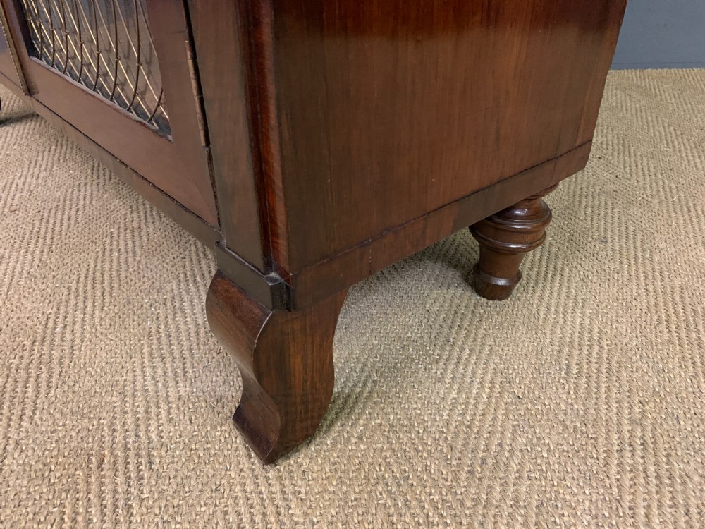 An antique Regency rosewood chiffonier featuring ornate brass inlay, a top mirror back with a brass gallery rail, and twin doors with brass wire mesh. View XIX