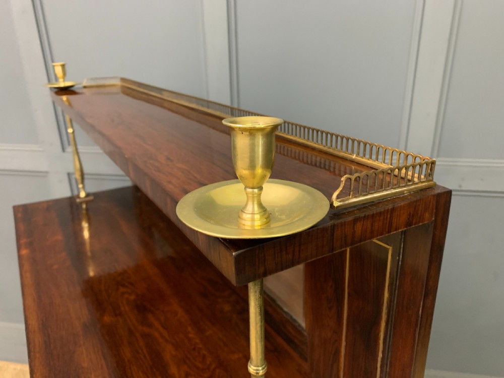 An antique Regency rosewood chiffonier featuring ornate brass inlay, a top mirror back with a brass gallery rail, and twin doors with brass wire mesh. View XXI