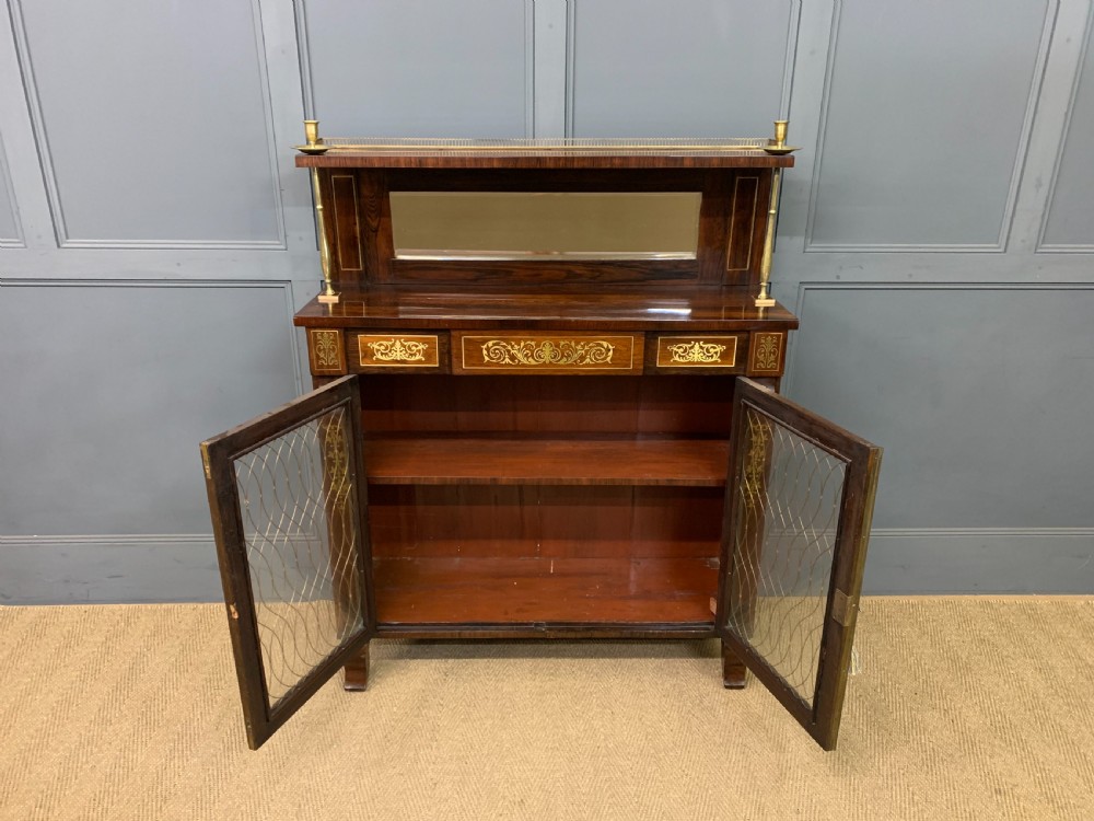 An antique Regency rosewood chiffonier featuring ornate brass inlay, a top mirror back with a brass gallery rail, and twin doors with brass wire mesh. View XXII
