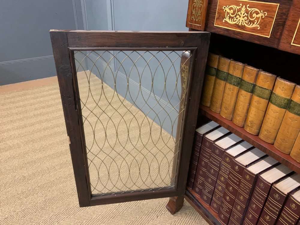 An antique Regency rosewood chiffonier featuring ornate brass inlay, a top mirror back with a brass gallery rail, and twin doors with brass wire mesh. View XXIV