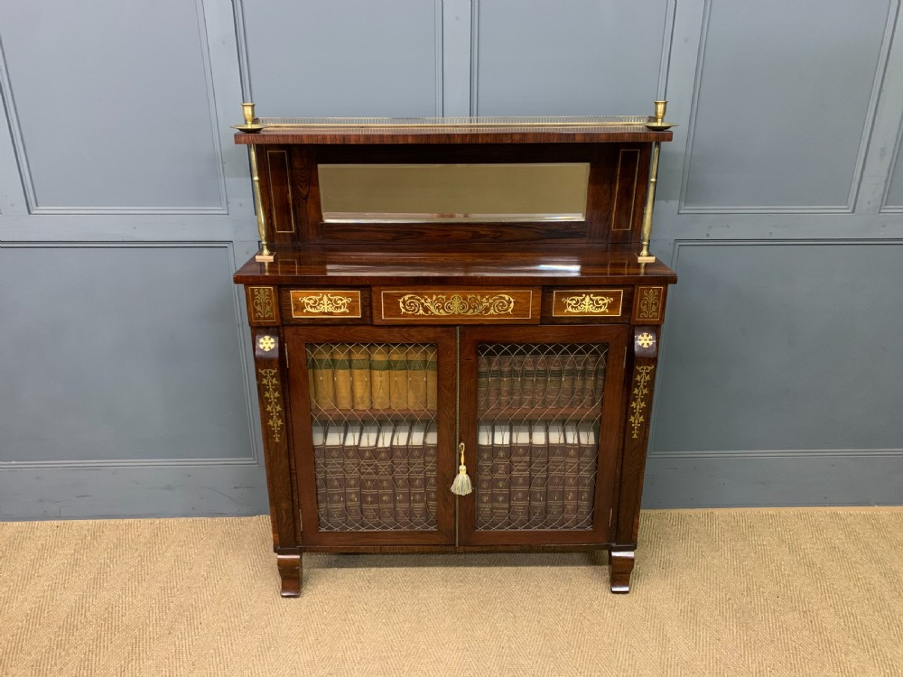 An antique Regency rosewood chiffonier featuring ornate brass inlay, a top mirror back with a brass gallery rail, and twin doors with brass wire mesh. View XXV