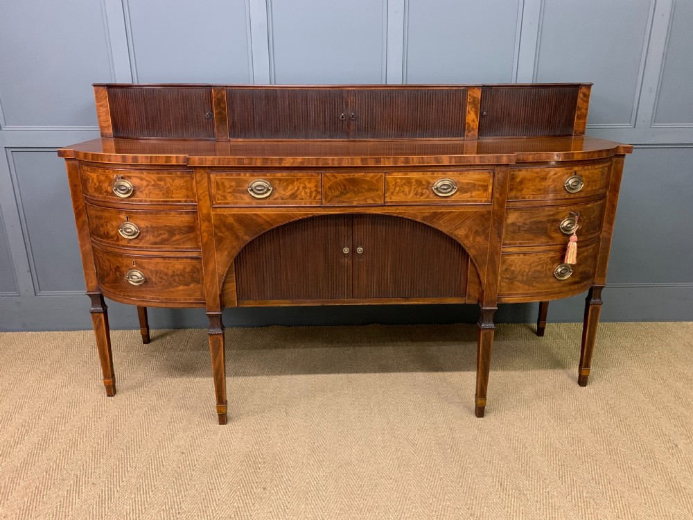 An antique George III inlaid mahogany sideboard with flame wood veneers, tambour doors, and brass ring drawer handles. View III