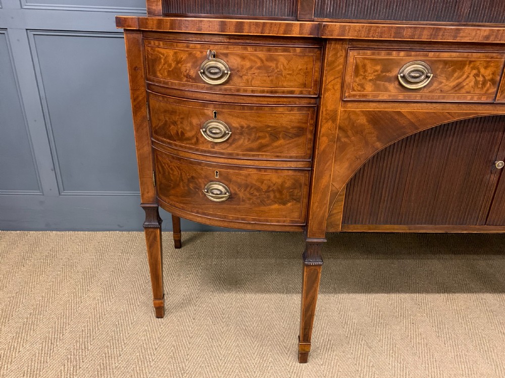 An antique George III inlaid mahogany sideboard with flame wood veneers, tambour doors, and brass ring drawer handles. View VI