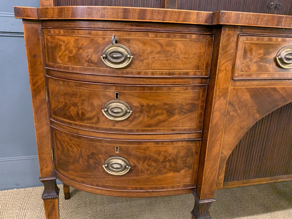 An antique George III inlaid mahogany sideboard with flame wood veneers, tambour doors, and brass ring drawer handles. View IX