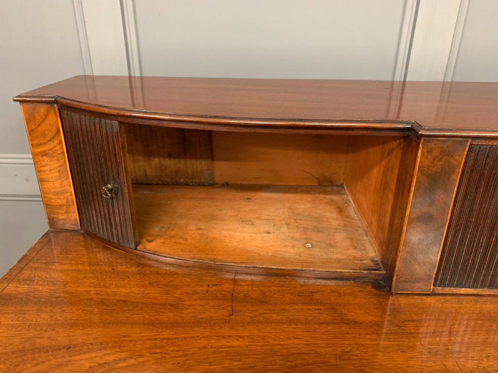 An antique George III inlaid mahogany sideboard with flame wood veneers, tambour doors, and brass ring drawer handles. View XIV