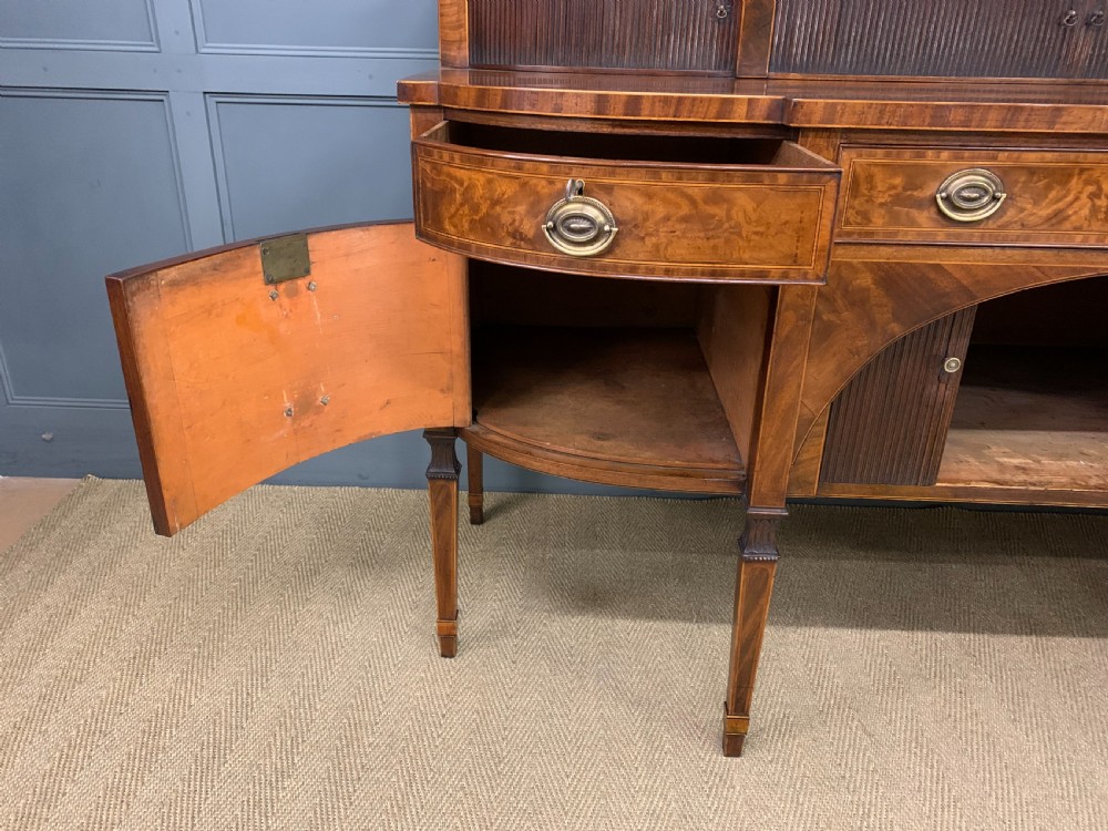 An antique George III inlaid mahogany sideboard with flame wood veneers, tambour doors, and brass ring drawer handles. View XV