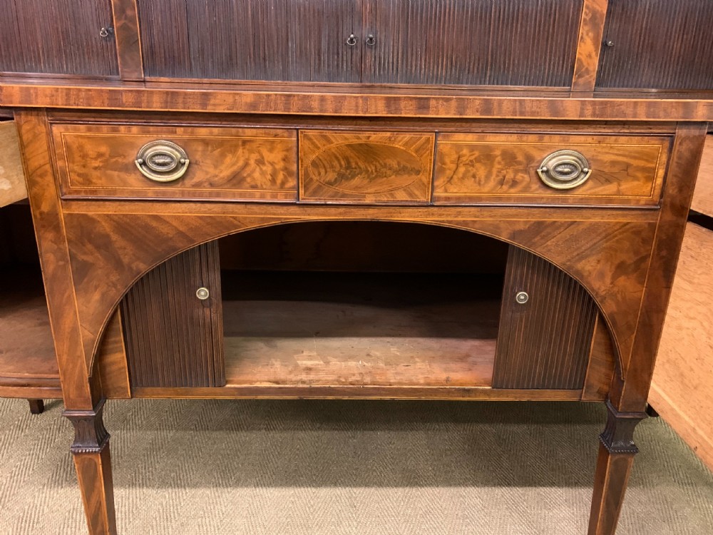 An antique George III inlaid mahogany sideboard with flame wood veneers, tambour doors, and brass ring drawer handles. View XVII