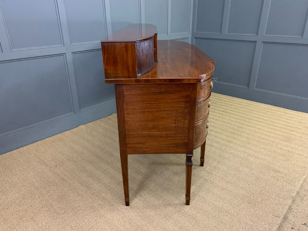 An antique George III inlaid mahogany sideboard with flame wood veneers, tambour doors, and brass ring drawer handles. View XIX