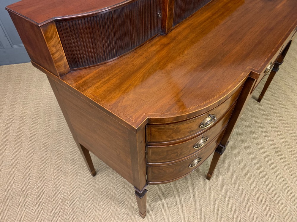 An antique George III inlaid mahogany sideboard with flame wood veneers, tambour doors, and brass ring drawer handles. View XX