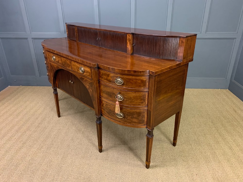 An antique George III inlaid mahogany sideboard with flame wood veneers, tambour doors, and brass ring drawer handles. View XXI
