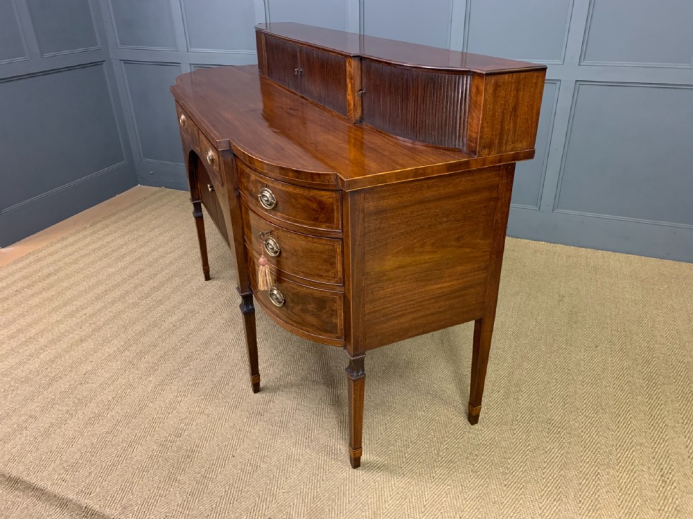 An antique George III inlaid mahogany sideboard with flame wood veneers, tambour doors, and brass ring drawer handles. View XXII