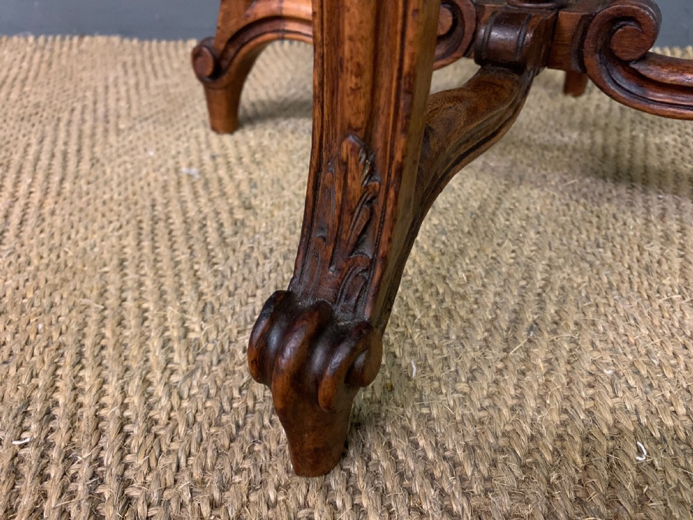A French carved walnut adjustable piano stool with cabriole legs, carved floral apron, X-shaped stretcher, and a round light yellow upholstered seat. View VI