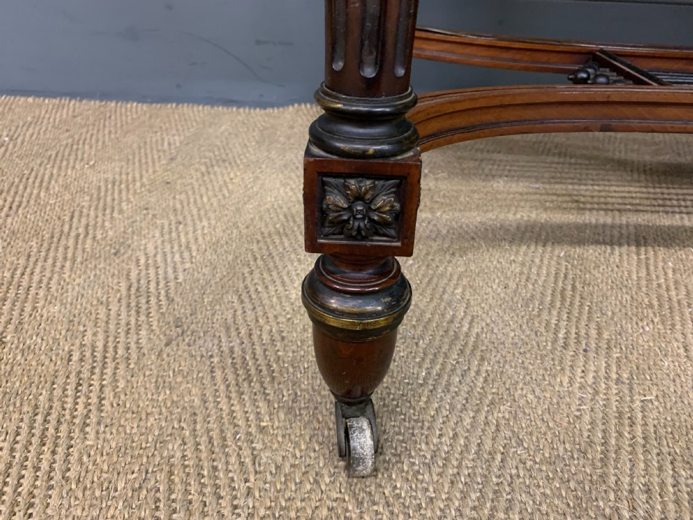 A rectangular French mahogany library table featuring a polished top, frieze drawer with carved detail, brass trim, turned fluted legs, and a lower carved stretcher on brass castors. View X