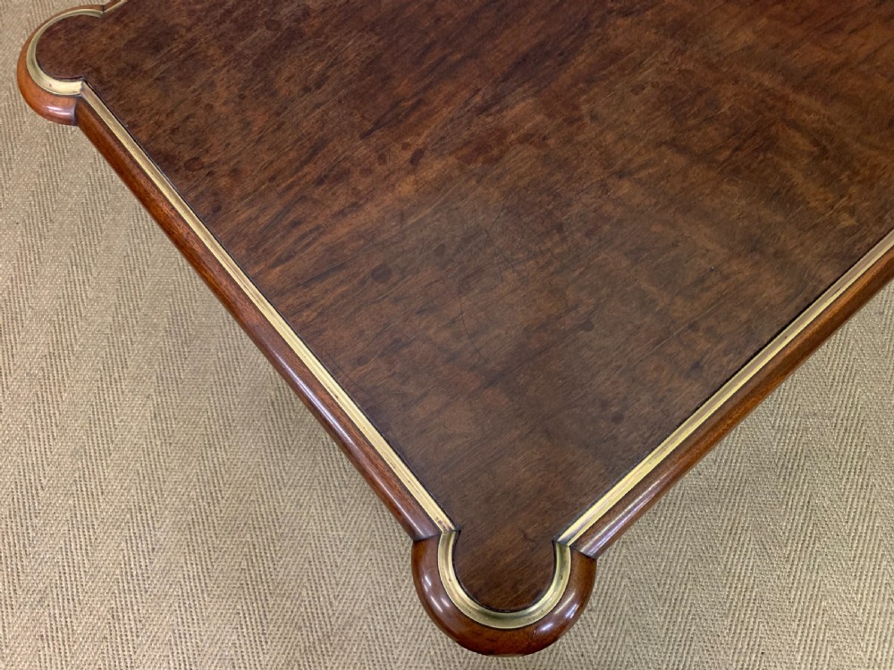 A rectangular French mahogany library table featuring a polished top, frieze drawer with carved detail, brass trim, turned fluted legs, and a lower carved stretcher on brass castors. View XII
