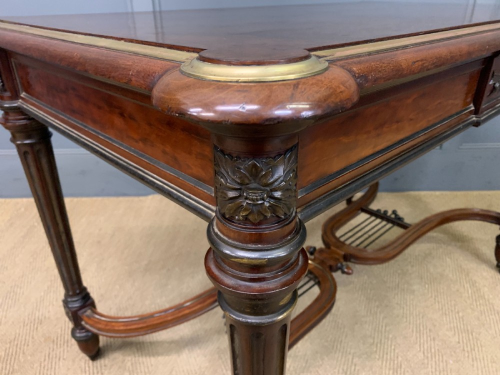 A rectangular French mahogany library table featuring a polished top, frieze drawer with carved detail, brass trim, turned fluted legs, and a lower carved stretcher on brass castors. View XIV