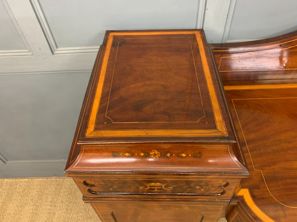 A George III inlaid mahogany pedestal sideboard featuring twin cupboard pedestals decorated with urn marquetry and a shaped backboard. View III