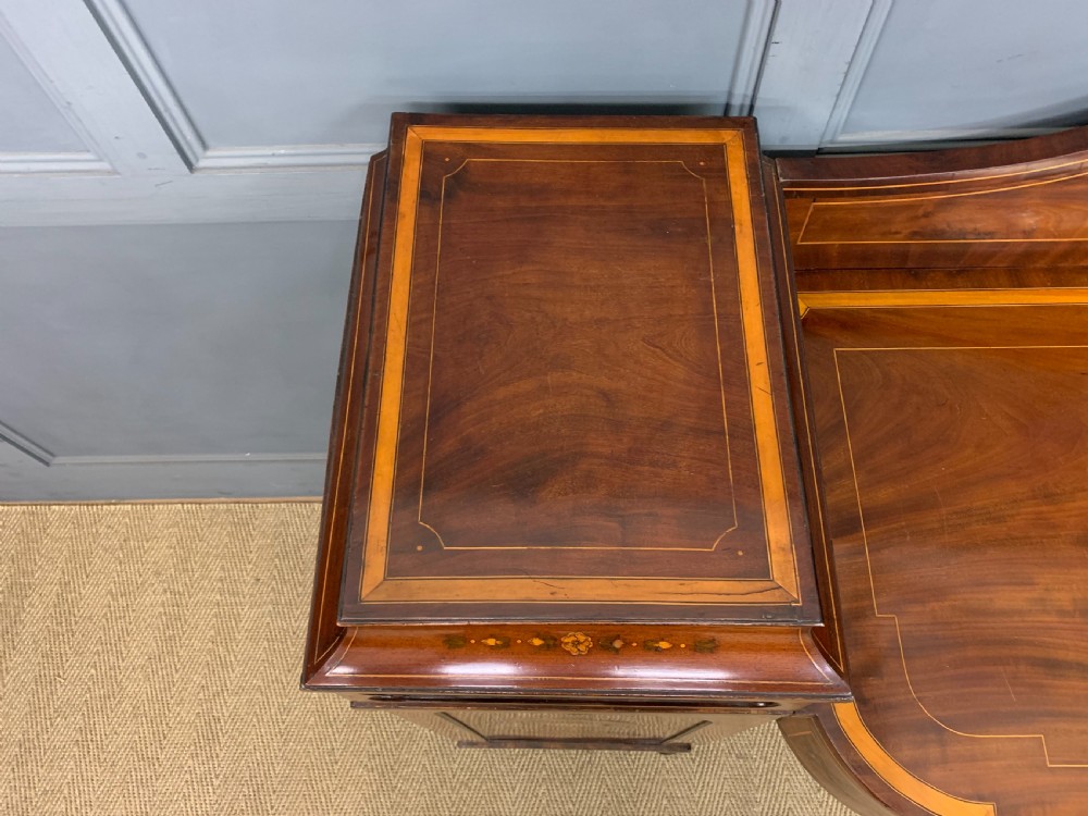 A George III inlaid mahogany pedestal sideboard featuring twin cupboard pedestals decorated with urn marquetry and a shaped backboard. View IV