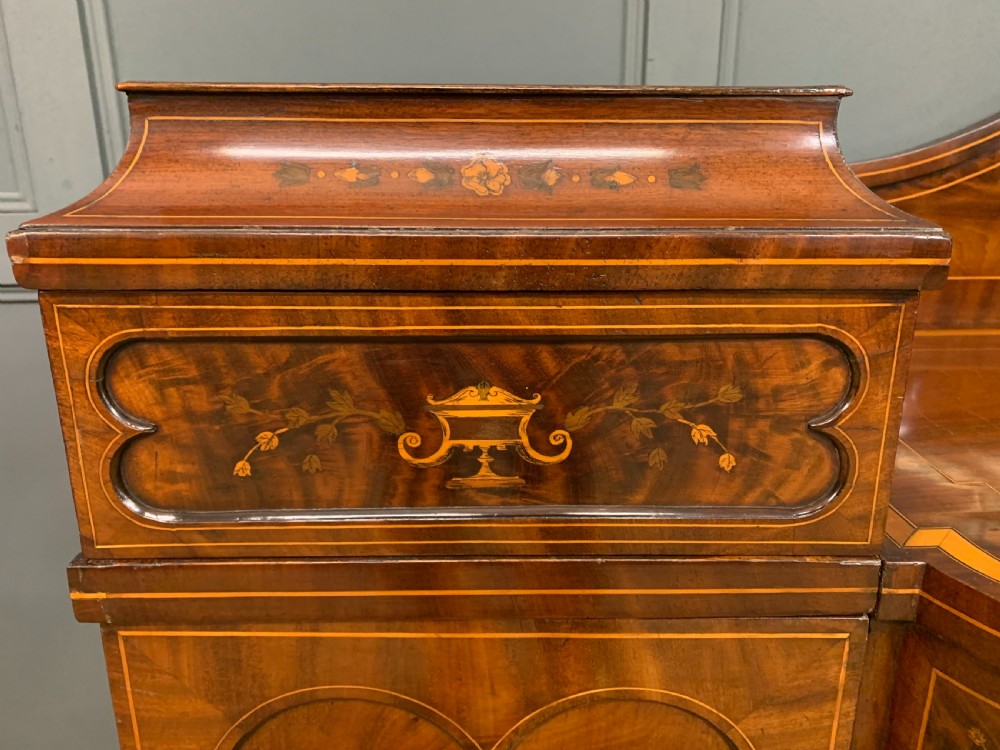 A George III inlaid mahogany pedestal sideboard featuring twin cupboard pedestals decorated with urn marquetry and a shaped backboard. View V
