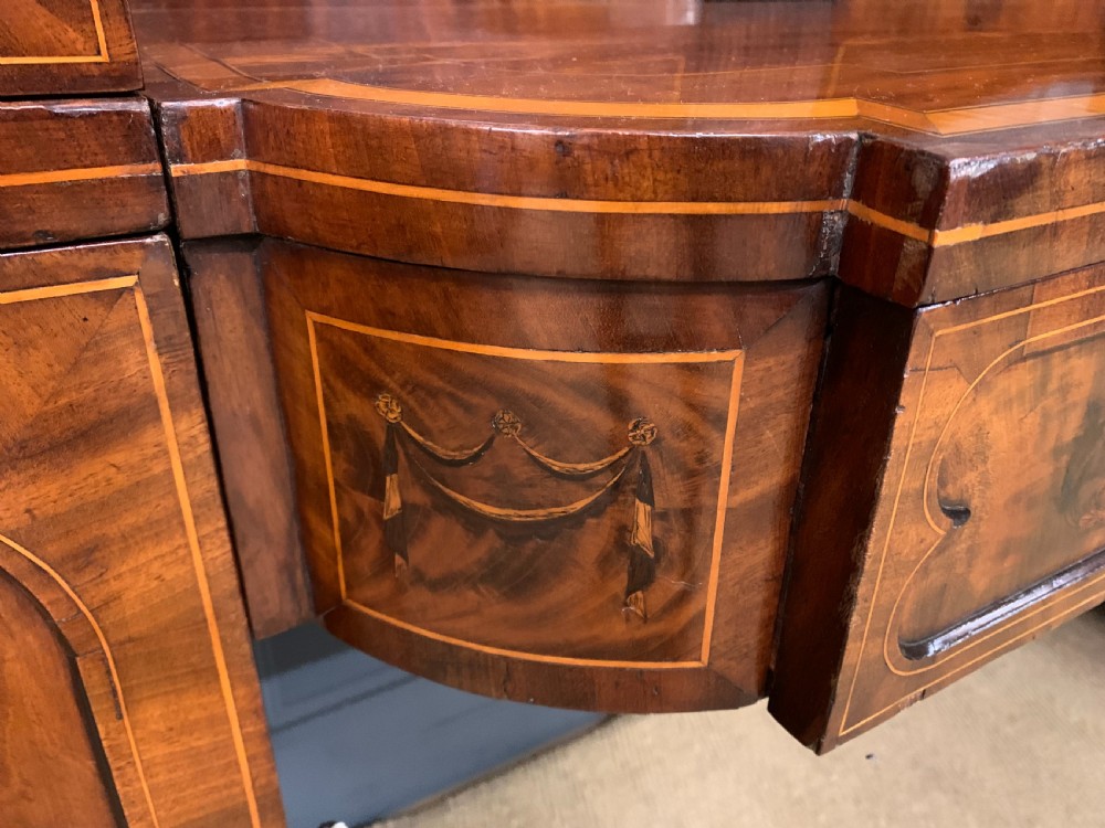 A George III inlaid mahogany pedestal sideboard featuring twin cupboard pedestals decorated with urn marquetry and a shaped backboard. View VIII