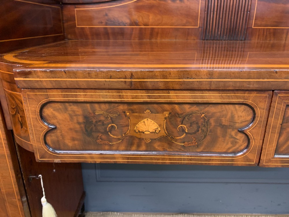 A George III inlaid mahogany pedestal sideboard featuring twin cupboard pedestals decorated with urn marquetry and a shaped backboard. View IX
