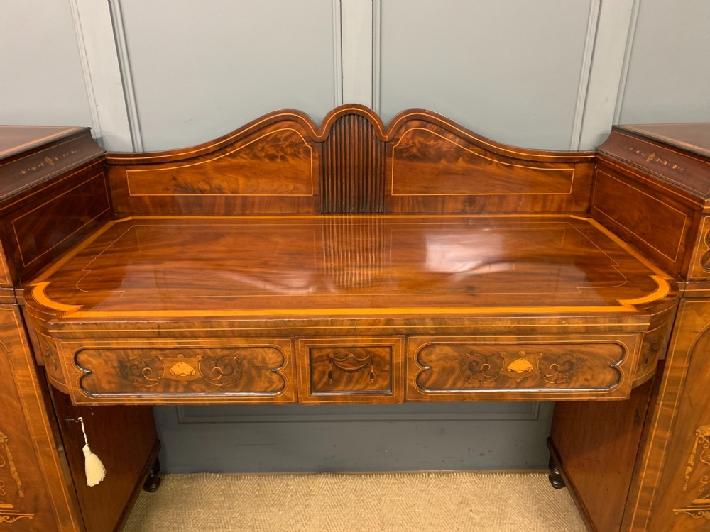 A George III inlaid mahogany pedestal sideboard featuring twin cupboard pedestals decorated with urn marquetry and a shaped backboard. View XI