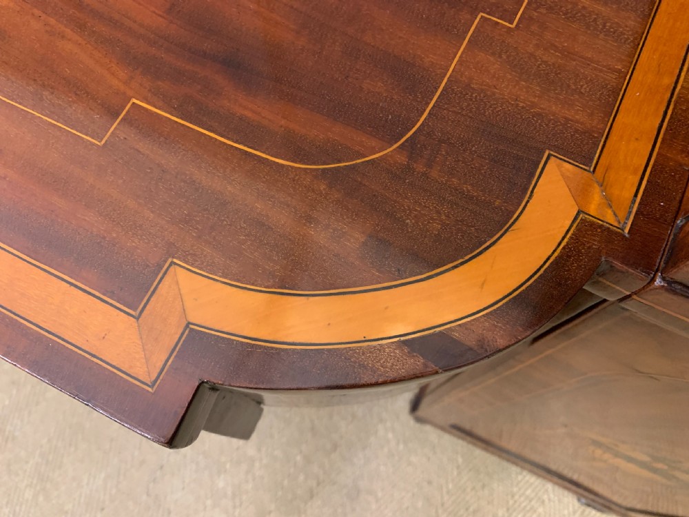 A George III inlaid mahogany pedestal sideboard featuring twin cupboard pedestals decorated with urn marquetry and a shaped backboard. View XIX