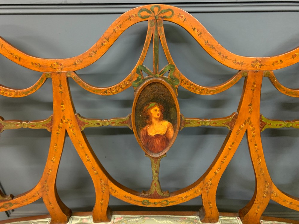 A painted satinwood three-seat settee with central portrait medallions and a light green floral upholstered cushion. View V
