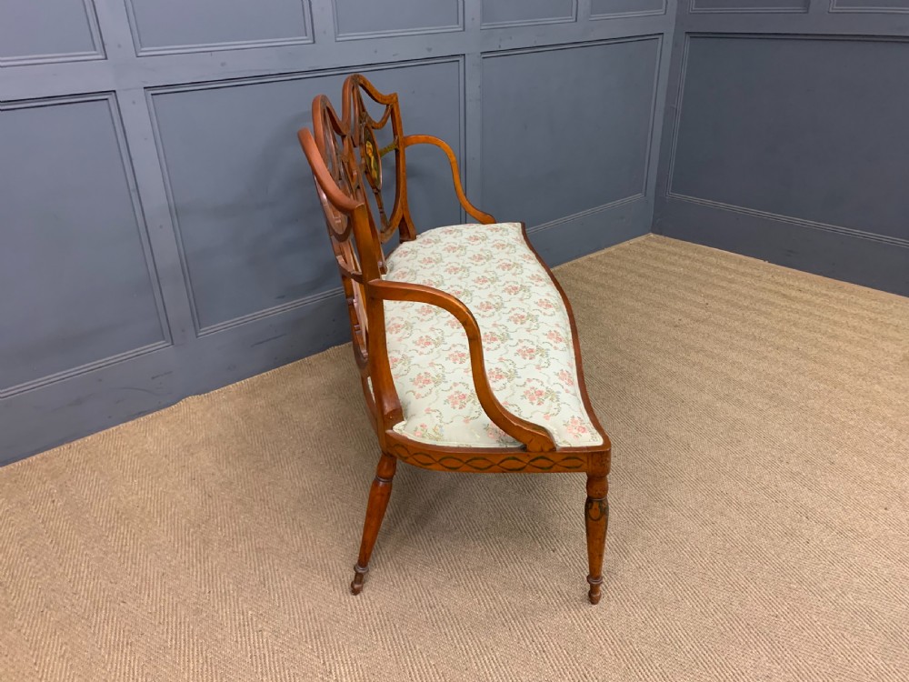 A painted satinwood three-seat settee with central portrait medallions and a light green floral upholstered cushion. View X