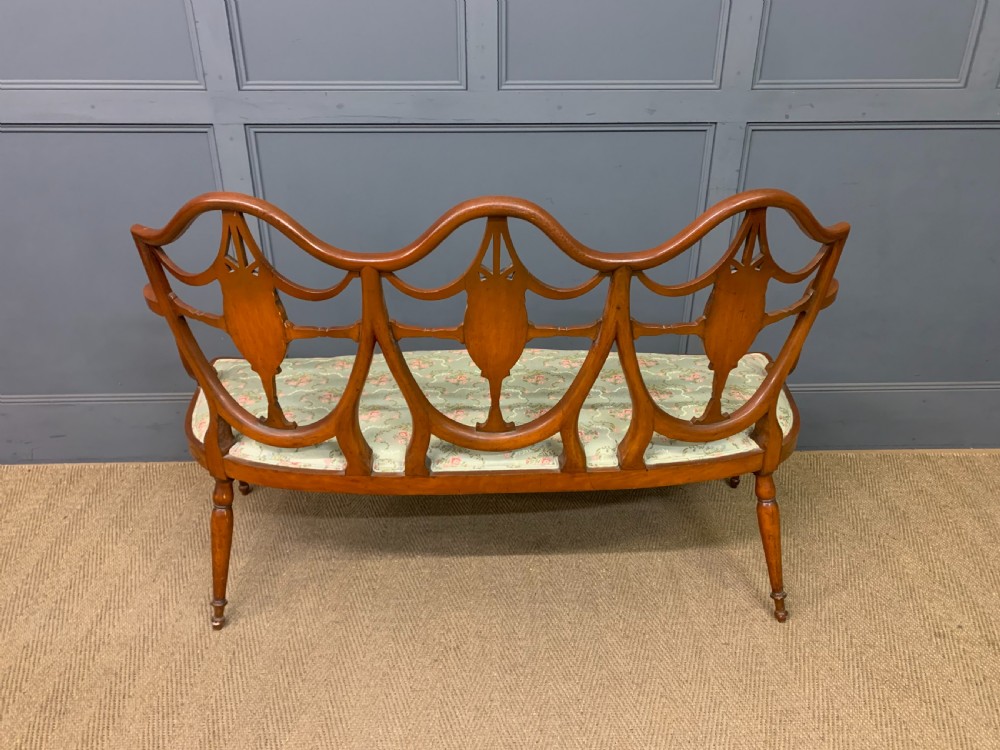 A painted satinwood three-seat settee with central portrait medallions and a light green floral upholstered cushion. View XIV