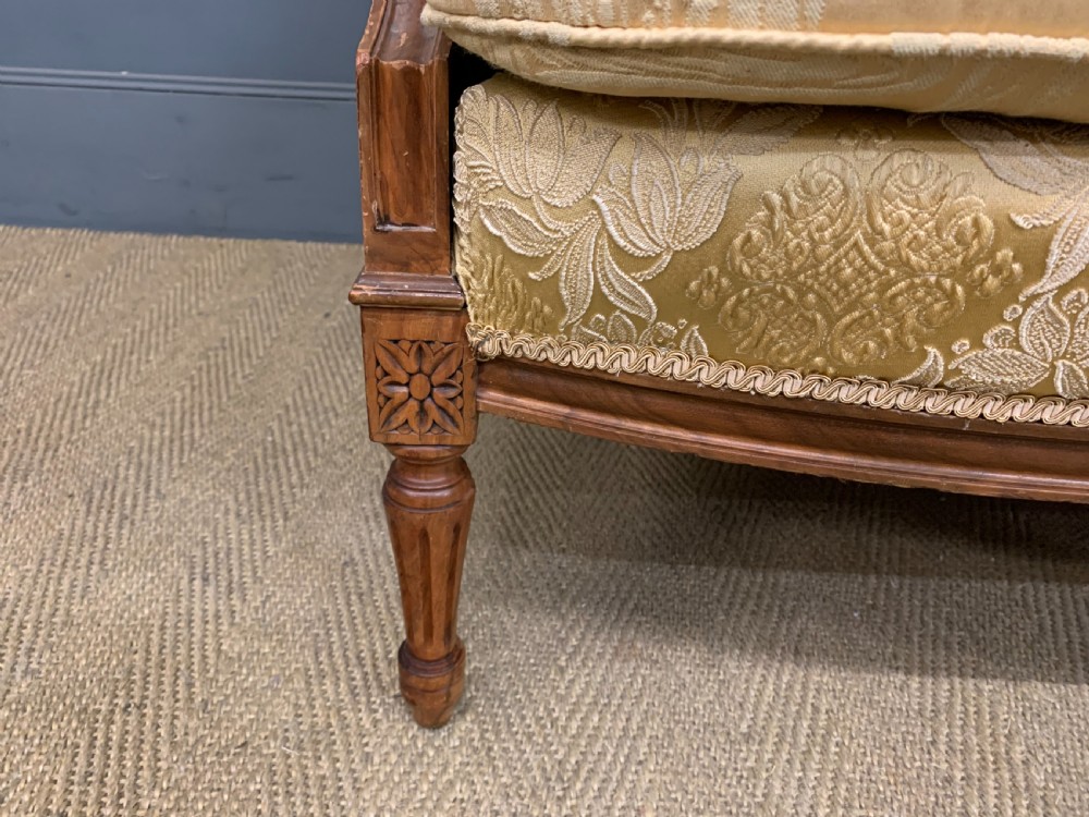 A three-piece French walnut salon suite featuring a sofa and two matching armchairs upholstered in gold patterned damask with deep buttoned backrests and fluted carved legs. View V