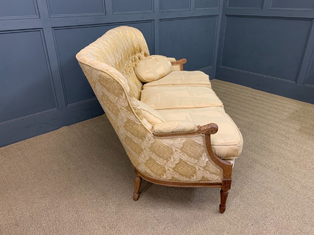 A three-piece French walnut salon suite featuring a sofa and two matching armchairs upholstered in gold patterned damask with deep buttoned backrests and fluted carved legs. View XI