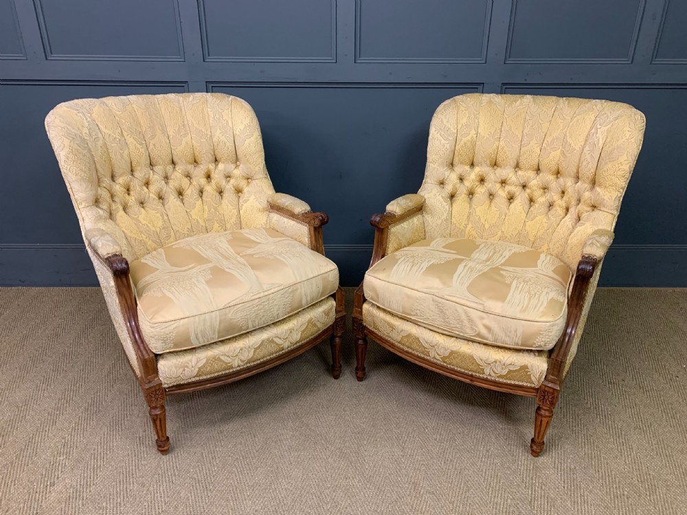 A three-piece French walnut salon suite featuring a sofa and two matching armchairs upholstered in gold patterned damask with deep buttoned backrests and fluted carved legs. View XV