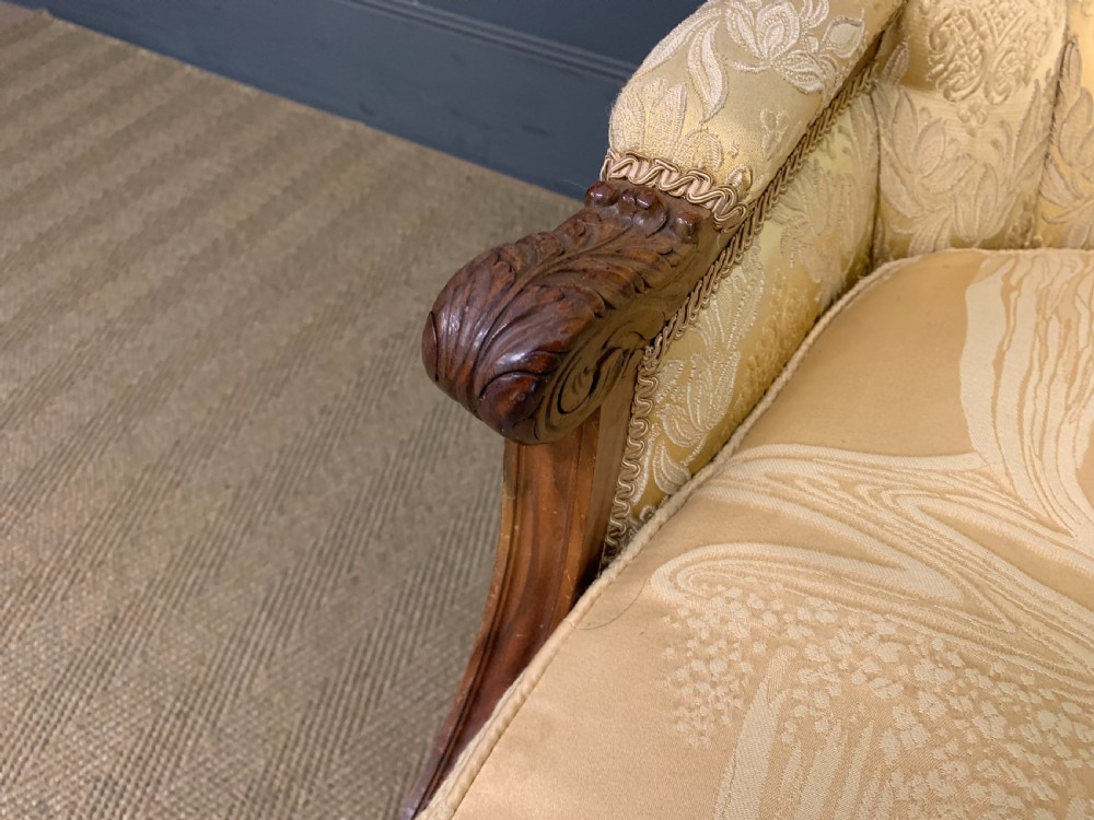 A three-piece French walnut salon suite featuring a sofa and two matching armchairs upholstered in gold patterned damask with deep buttoned backrests and fluted carved legs. View XVI