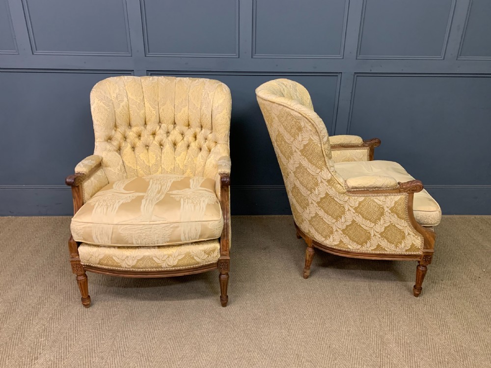 A three-piece French walnut salon suite featuring a sofa and two matching armchairs upholstered in gold patterned damask with deep buttoned backrests and fluted carved legs. View XVII
