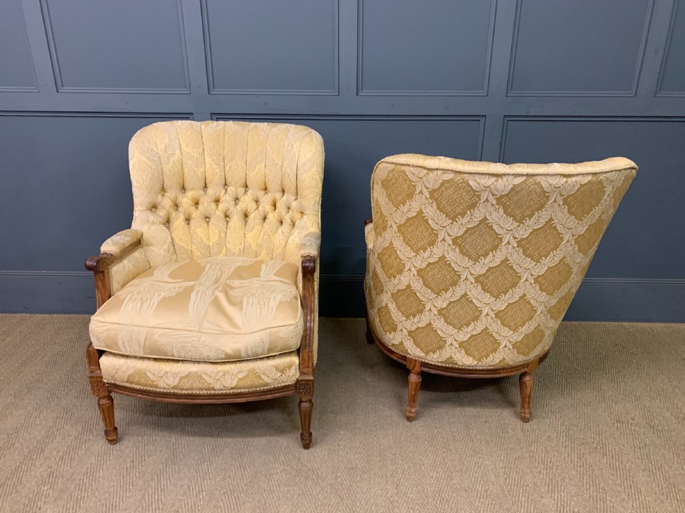 A three-piece French walnut salon suite featuring a sofa and two matching armchairs upholstered in gold patterned damask with deep buttoned backrests and fluted carved legs. View XVIII