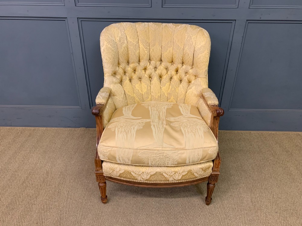 A three-piece French walnut salon suite featuring a sofa and two matching armchairs upholstered in gold patterned damask with deep buttoned backrests and fluted carved legs. View XIX